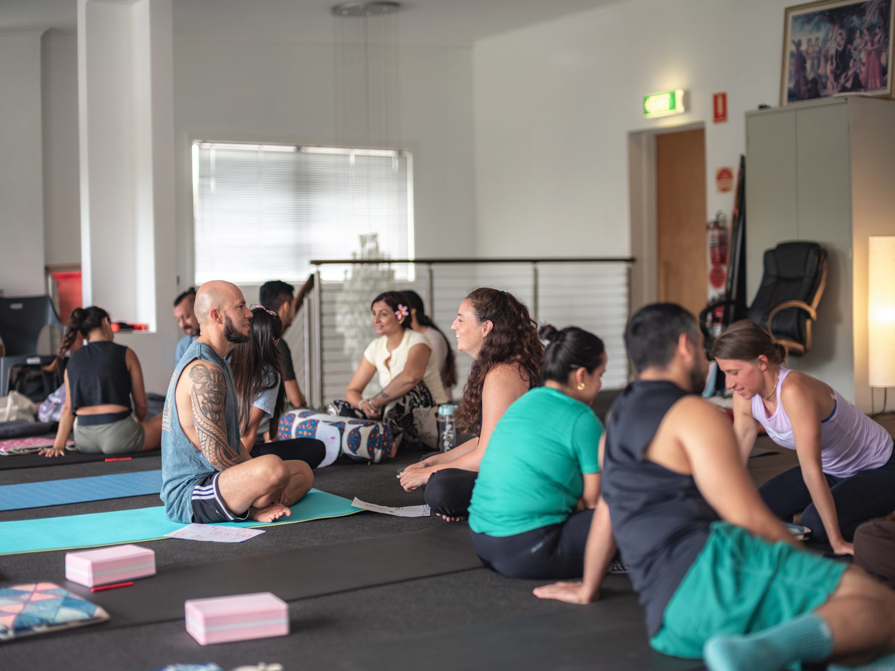 A group of people sitting on yoga mats in the studio