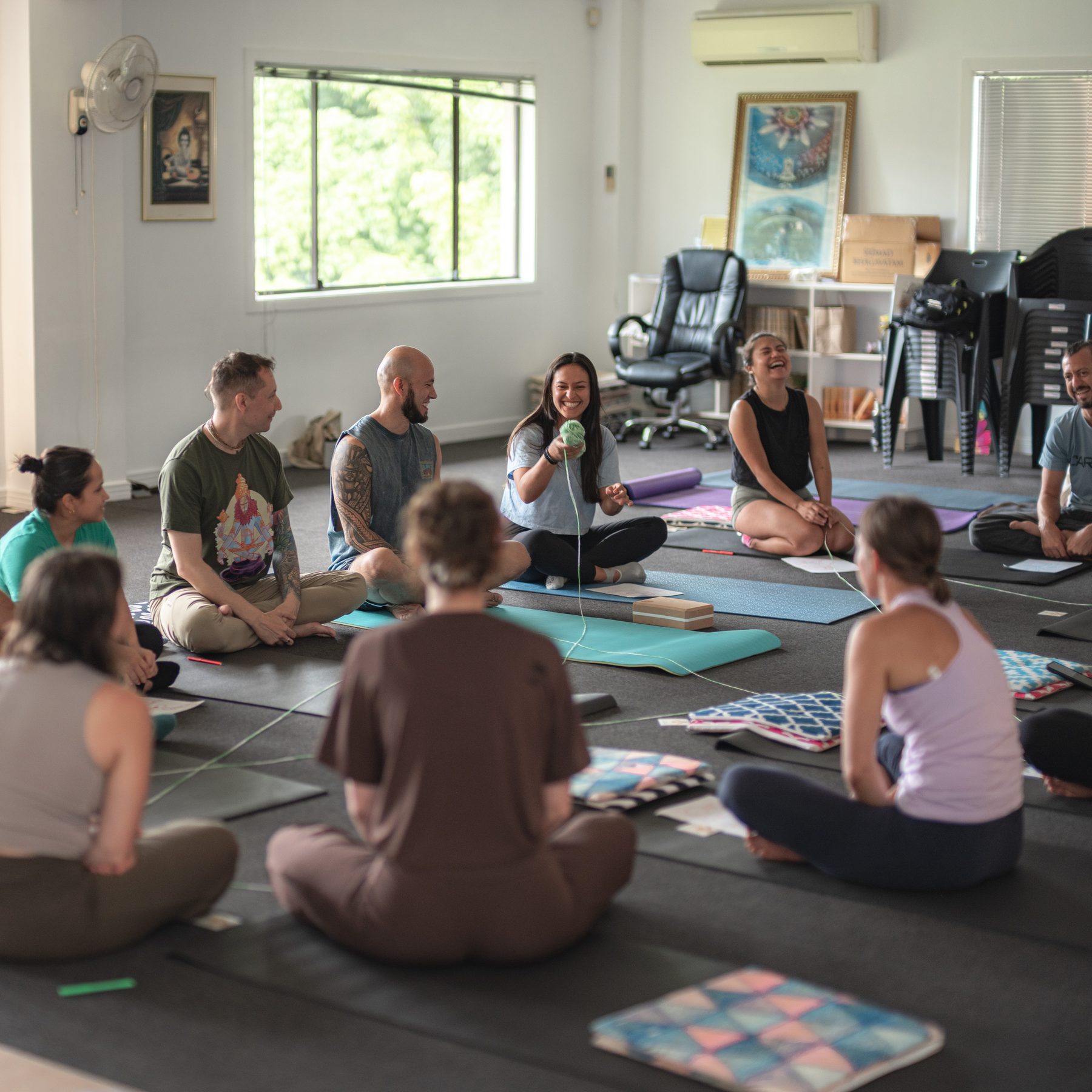 A group of people sitting in a circle on yoga mats in the studio